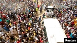 Supporters welcome Muhammadu Buhari (in vehicle), presidential candidate from the All Progressives Congress party, as he visits a Gombe regional leader during an election rally in Gombe, Nigeria, February 3, 2015. 