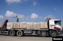 FILE - A Palestinian worker stands atop a truck loaded with bags of cement after entering Gaza, at the Kerem Shalom crossing in Rafah in the southern Gaza Strip, Nov. 10, 2014.