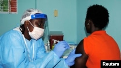 A health worker injects a woman with an Ebola vaccine during a trial in Monrovia, Feb. 2, 2015. 