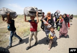 Iraqi families are seen near al-Sejar village in Anbar province, after fleeing the city of Fallujah, May 27, 2016, during a major operation by pro-government forces to retake the city from the Islamic State (IS) group.