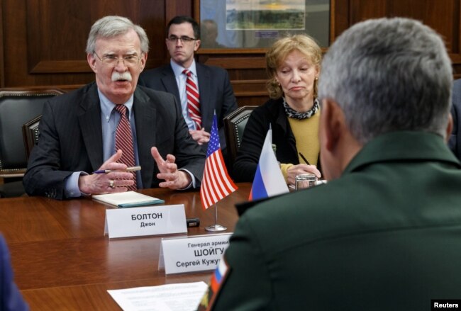 Russia's Defense Minister Sergei Shoigu, back to camera, meets with U.S. national security adviser John Bolton in Moscow, Oct. 23, 2018.