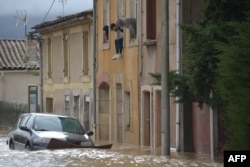 Residents look from their window above cars standing in a flooded street following heavy rains that saw rivers bursting banks on Oct. 15, 2018 in Trebes, near Carcassone, southern France.