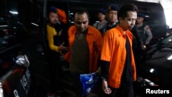 Indonesian policemen stand guard as Ahmad Junaedi, right, and Aprimul Henry alias Mulbin Arifin, center, who are accused of supporting Islamic State, arrive for their trial in Jakarta, Feb. 9, 2016.