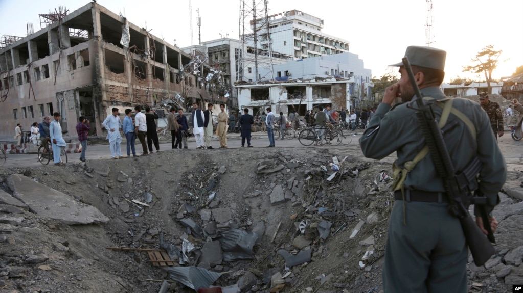 2017年5月31日，阿富汗安全部隊士兵站在喀布爾德國駐阿富汗使館前一處由當天巨大卡車炸彈爆炸形成的大坑旁。
