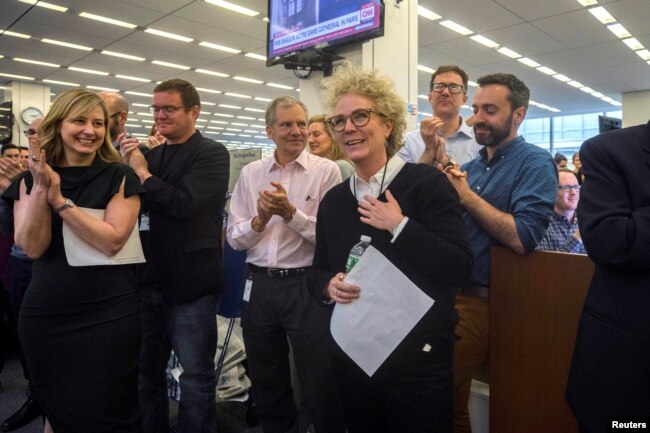 La periodista del New York Times, Susanne Craig, quien junto con sus colegas David Barstow y Russ Buettner ganaron el Premio Pulitzer 2019 para la presentación de informes explicativos por su revisión forense de las finanzas familiares del presidente Donald Trump, es aplaudida por el personal del diario en Nueva York.