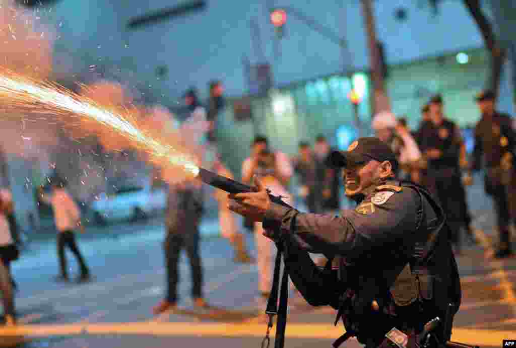 A riot police officer fires tear gas at violent demonstrators after clashes erupted following a march by Brazilian workers in Rio de Janeiro in a day of industrial action called by major unions to press demands for better work conditions.