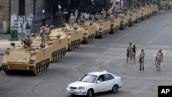 FILE - Egyptian army soldiers take their positions on top and next to their armored vehicles to guard an entrance of Tahrir Square, in Cairo, August 2013.