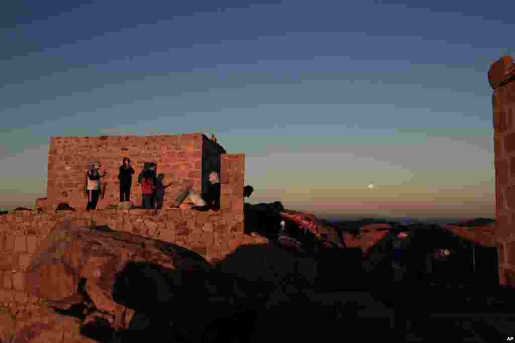 Arab tourists, left and American tourists, right, watch the sun rise and the moon set from the top of Mount Sinai or &#39;Mount Moses&#39; in Saint Catherine in the Sinai peninsula, Egypt.