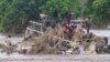 In this image made from video, people stand on an overturned vehicle swept by flooding waters in Chikwawa, Malawi, Jan. 25, 2022.