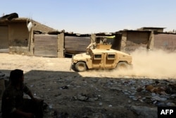 FILE - A fighter waves the flag of the Kurdish People's Protection Units (YPG) from atop an armed vehicle driving through Raqqa, Syria, Aug. 13, 2017.