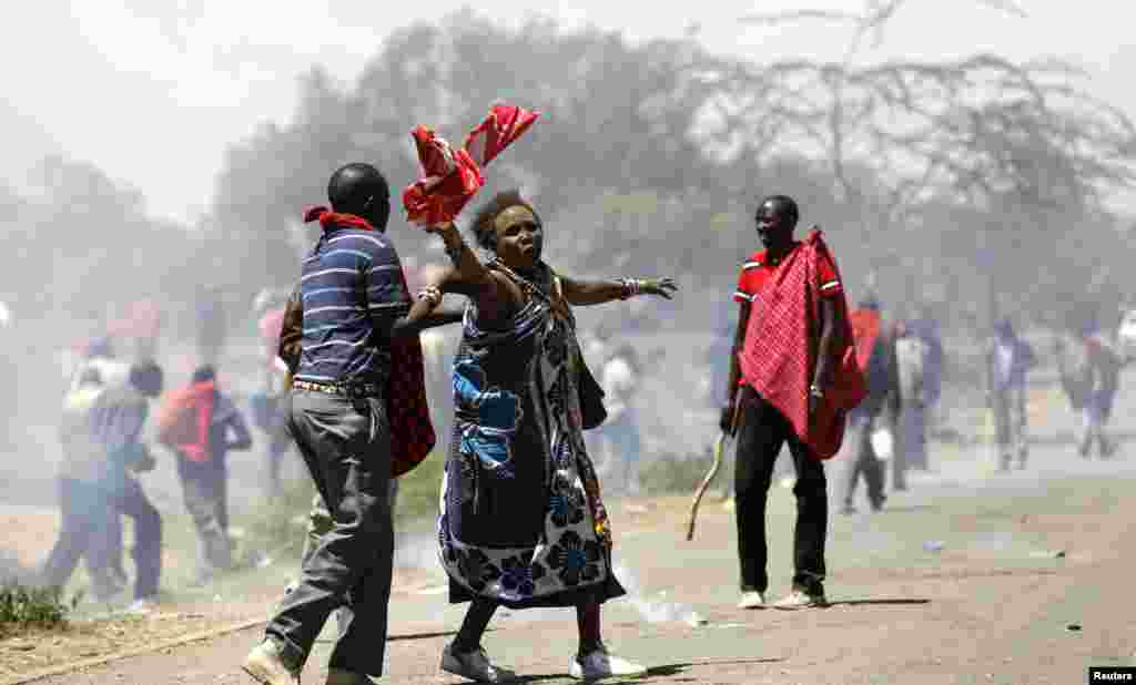 An elderly woman is assisted after riot policemen fired teargas canisters to disperse protests to oust the Narok county Governor Samuel Tunai in Narok, Kenya.