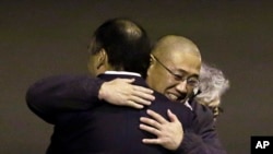 FILE - Kenneth Bae, center, who had been held in North Korea since 2012, is hugged after arriving at Joint Base Lewis-McChord, Washington, Nov. 8, 2014.
