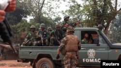 A French soldier looks on as a soldiers from the Multinational Force of Central Africa (FOMAC) drive past in Bangui, Dec. 26, 2013. 