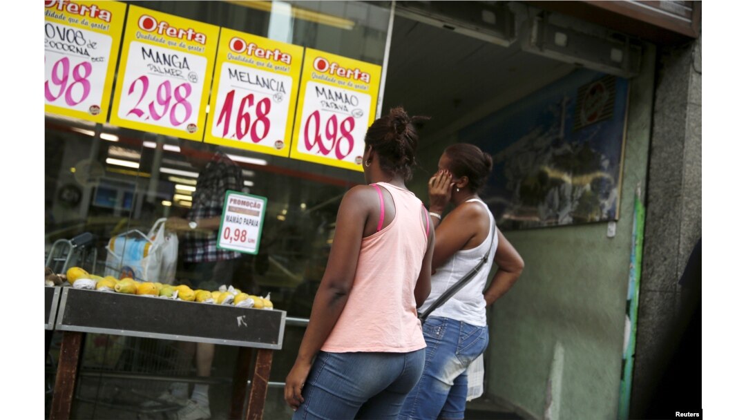 FILE - Women look at prices at a food market in Rio de Janeiro, Brazil, Jan. 21, 2016.