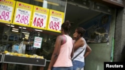 Women look at prices at a food market in Rio de Janeiro, Brazil, Jan. 21, 2016.