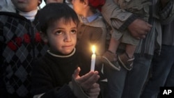 A Palestinian boy holds a candle during a protest in the northern Gaza Strip to mark the second anniversary of Israel's three-week offensive in Gaza, 27 Dec 2010.