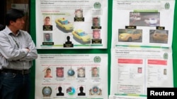A journalist looks at posters detailing the arrest operation of a suspect in the death of U.S. Drug Enforcement Administration Special Agent James "Terry" Watson, in Bogota, Colombia, June 25, 2013. 