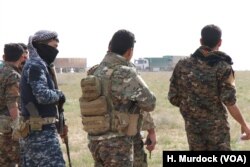 Internationally-backed Syrian Democratic Forces watch as trucks filled with people evacuate Baghuz, IS's last stronghold in Syria on Feb. 26, 2019, near Baghuz.