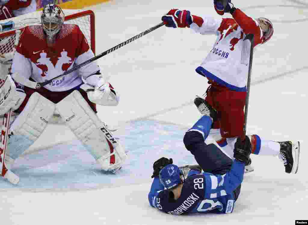 Lauri Korpikoski (28) dari Finlandia memukul Alexei Yemelin dari Rusia (kanan) seraya penjaga gawang dari Rusia, Semyon Varmalov mengikuti arah bola pada babak kedua babak perempat final hoki es. Finlandia menang 3-1. &nbsp;