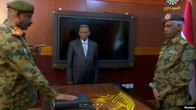 Sudan’s defense minister, Awad Mohamed Ahmed Ibn Auf, head of the Military Transitional Council, looks on as the military’s chief of staff, Lt. Gen. Kamal Abdul Murof Al-mahi, is sworn in as a deputy head of Military Transitional Council in Sudan, April 11, 2019.