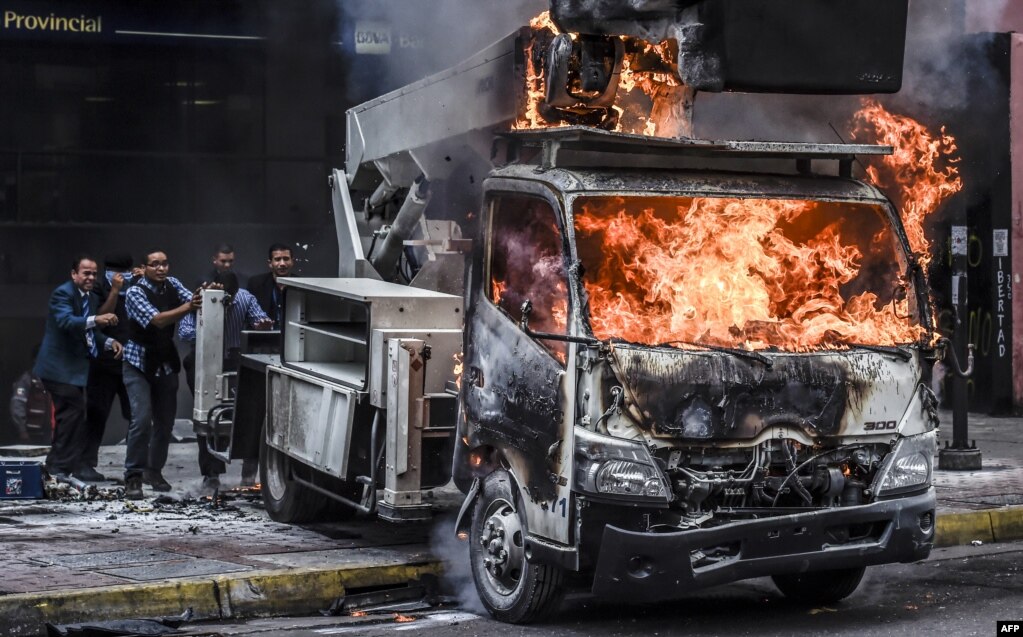 지난 7일(현지시간) 베네수엘라 반정부 시위대가 불붙인 트럭을 최고법원 관계자들이 청사 밖으로 밀어내고 있다.