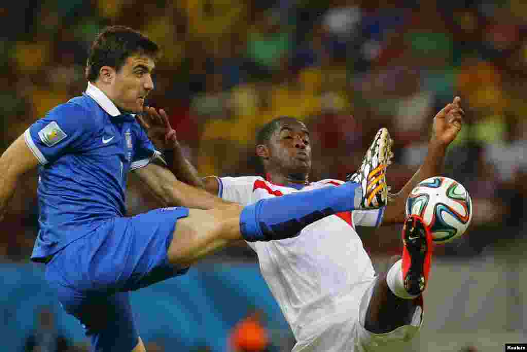 Greece's Sokratis Papastathopoulos, left, fights for the ball with Costa Rica's Joel Campbell at the Pernambuco arena in Recife, June 29, 2014.