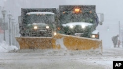 FILE - Snow plows clear a street during a snowstorm, Feb. 12, 2017, in Waltham, Mass. 