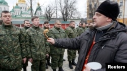 An Orthodox priest blesses members of the newly created Ukrainian interior ministry battalion "Saint Maria" during a ceremony before they head to militay training, in front of St. Sophia Cathedral, in Kyiv, Feb. 3, 2015. 