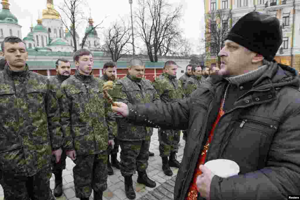 An Orthodox priest blesses members of the newly-created Ukrainian Interior Ministry battalion &quot;Saint Maria&quot; during a ceremony before they head to militay training, in front of St. Sophia Cathedral, in Kyiv, Feb. 3, 2015.