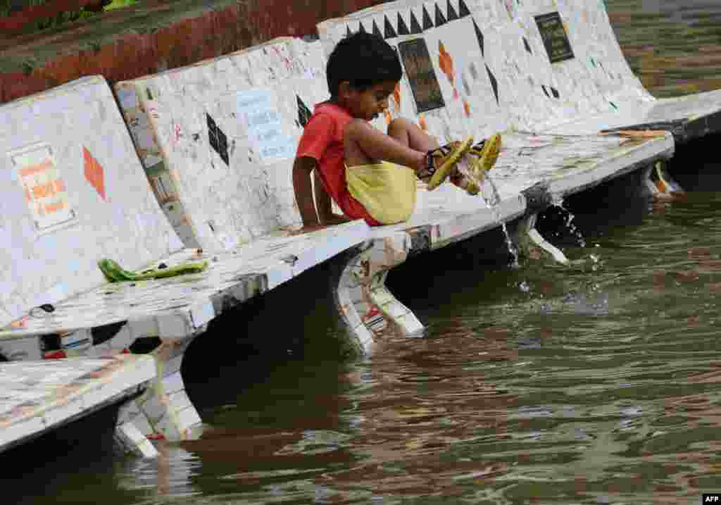 인도 아흐메다바드 시내가 폭우로 범람한 가운데, 어린아이가 물가에서 장난을 치고 있다.