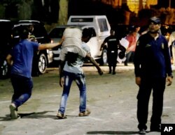 A wounded man is carried from the site of a car bomb explosion near a national security building in a residential neighborhood in Cairo, Aug. 20, 2015.