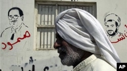 A Bahraini man passes a wall bearing depictions of jailed Bahraini opposition figures Ebrahim Sharif (L), with the word "steadfast" sprayed in red, and Sheik Mohamed Habib Moqdad (R), with the words "We will never forget you" and above graffiti reading "G