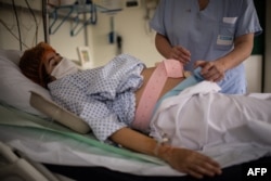 Seorang perawat tengah membantu ibu hamil yang terpapar COVID-19 di Paris, Prancis, 17 November 2020. (Martin BUREAU / AFP)