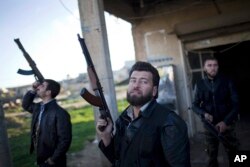 FILE - Free Syrian Army fighters look at a Syrian Army jet, not pictured, in Fafeen village, north of Aleppo province, Syria.