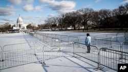 A pedestrian stands at the intersection of barricades dividing areas of standing room on the National Mall in Washington, Jan. 18, 2017, as preparations continue for Friday's presidential inauguration.
