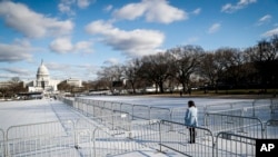 A pedestrian stand at the intersection of barricades dividing areas of standing room on the National Mall in Washington, Jan. 18, 2017, as preparations continue for Friday's presidential inauguration.