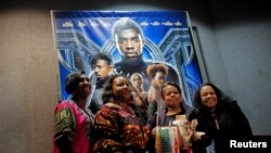 Sekelompok pengunjung berpose di depan poster film "Black Panther" pada malam pemutaran perdana di bioskop AMC Magic Johnson Harlem 9 di Manhattan, New York, AS, 15 Februari 2018. (Foto: dok).
