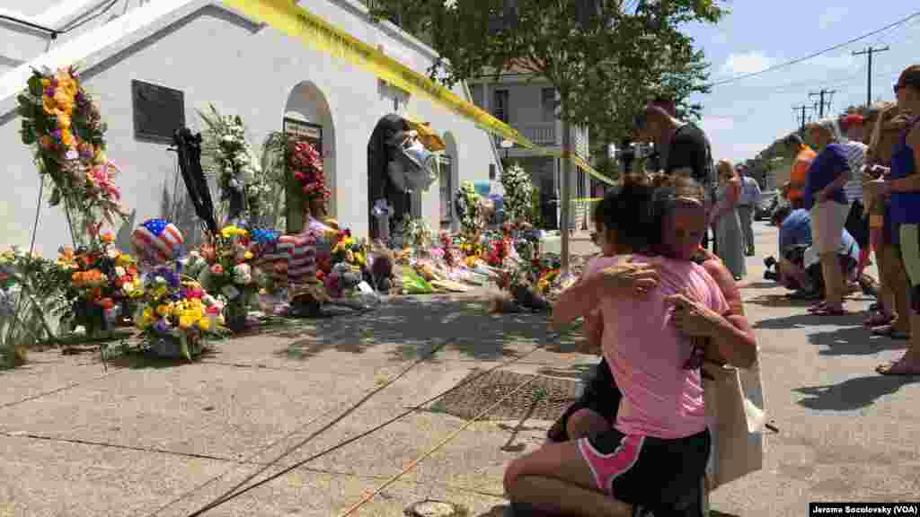 Mourners comfort each other in front of the Emanuel African Methodist Episcopal Church in Charleston, S.C., two days after a shooting left nine dead.