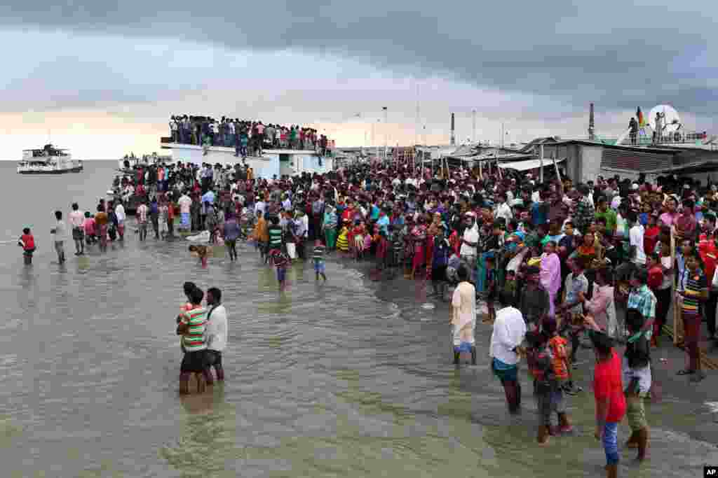 People crowd the banks and wade into the waters of the River Padma seeking news of survivors in Munshiganj district, Bangladesh, Monday, Aug. 4, 2014.