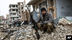 A Syrian Kurdish sniper sits among the rubble in the Syrian city of Kobani, Jan. 30, 2015.