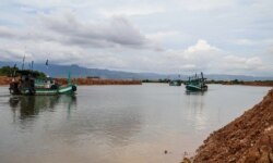 Fishermen navigate their boats near a development area where a part of Teuk Chhou bay is infilled, affecting fishstock in Kampot province, on October 3, 2021. (Sun Narin/វីអូអេ)