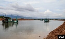 Fishermen navigate their boats near a development area where a part of Teuk Chhou bay is infilled, affecting fishstock in Kampot province, on October 3, 2021. (Sun Narin/វីអូអេ)