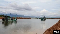 Fishermen navigate their boats near a development area where a part of Teuk Chhou bay is infilled, affecting fish stock in Kampot province, on October 3, 2021.