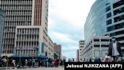 Des personnes font la queue pour obtenir des dollars américains dans les banques tôt le matin, certains ayant dormi dans la file d'attente un jour avant Noël, à Harare le 24 décembre 2021.