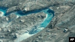 In this image taken on Thursday Aug.1, 2019 large rivers of melting water form on an ice sheet in western Greenland and drain into moulin holes that empty into the ocean from underneath the ice. (Photo via Caspar Haarløv, Into the Ice via AP)