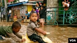 Anak-anak bermain di genangan air setelah hujan deras di Kampung Melayu, Jakarta Selatan. (Foto: VOA)