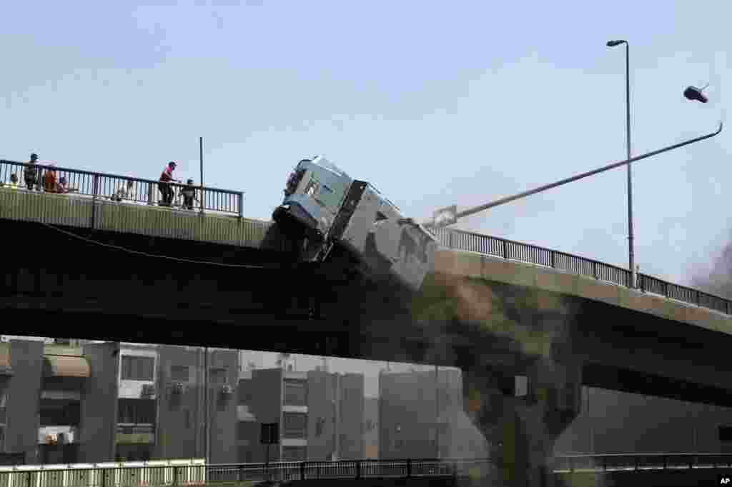 A police vehicle is pushed off of the 6th October bridge by supporters of ousted Islamist President Mohamed Morsi in the eastern Nasr City district of Cairo, Egypt.