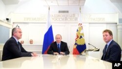 Russian President Vladimir Putin, center, watches the opening ceremony of natural gas pipeline from Russia to Crimea during a live video link from the Kremlin in Moscow, Dec. 27, 2016.