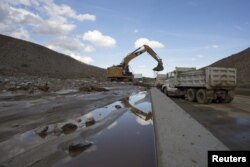 Workers dig out cars and trucks mired in mud and debris on State Route 58 near Tehachapi, California, about 97 kilometers (67 miles) outside of Los Angeles, Oct. 17, 2015.