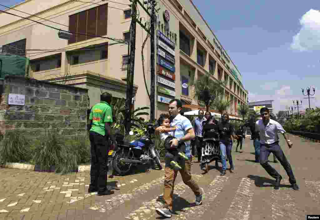 Customers run following a shootout between unidentified armed men and the police at the Westgate Shopping Center in Nairobi, Sept. 21, 2013.